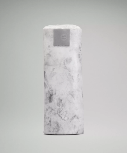 Photo of "the towel" from Lululemon, a white and gray marble print towel rolled into a tube, standing on end vertically